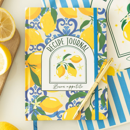 Recipe journal with lemon design on a white surface with lemons and a pen.