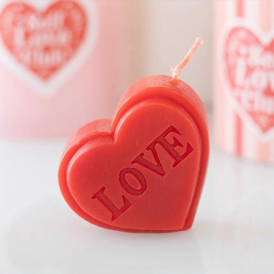 Heart-shaped candle with 'LOVE' text on a light background