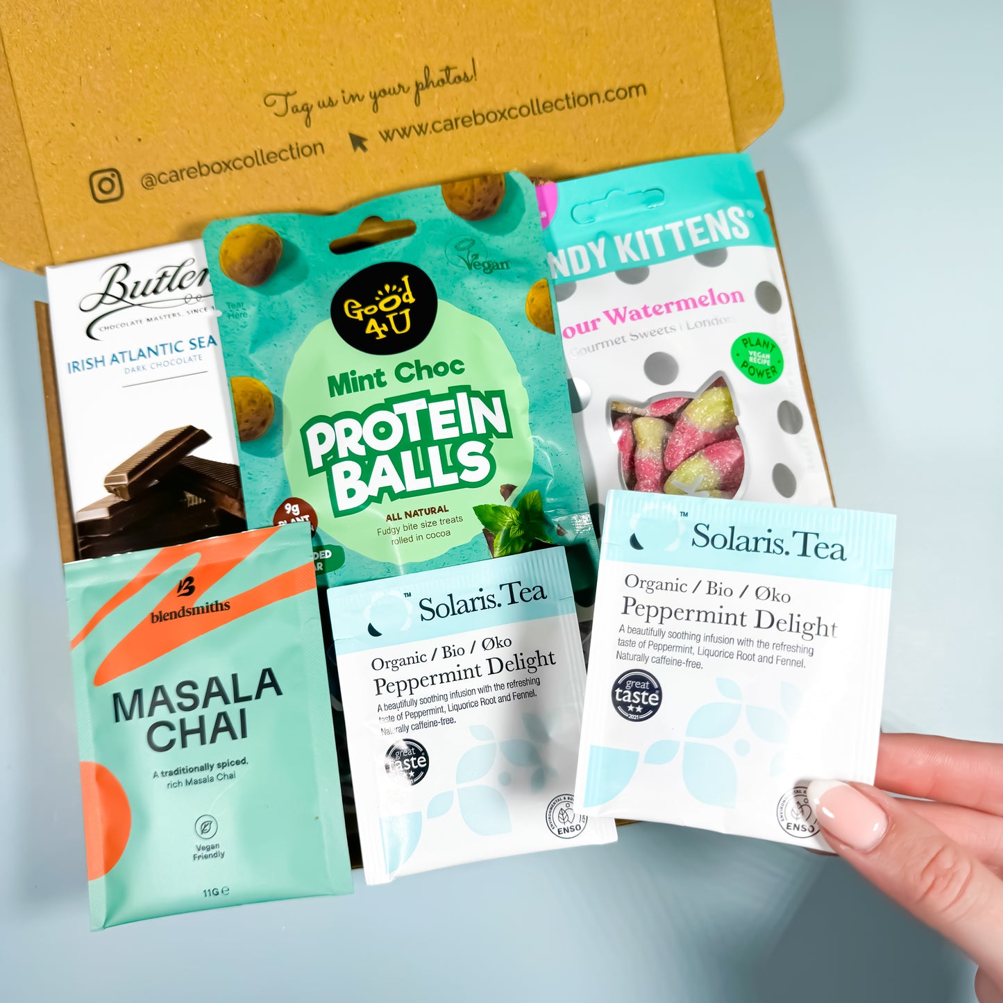 Minty Moments gift box with peppermint tea, masala chai, dark chocolate, sour watermelon sweets, and mint choc protein balls.