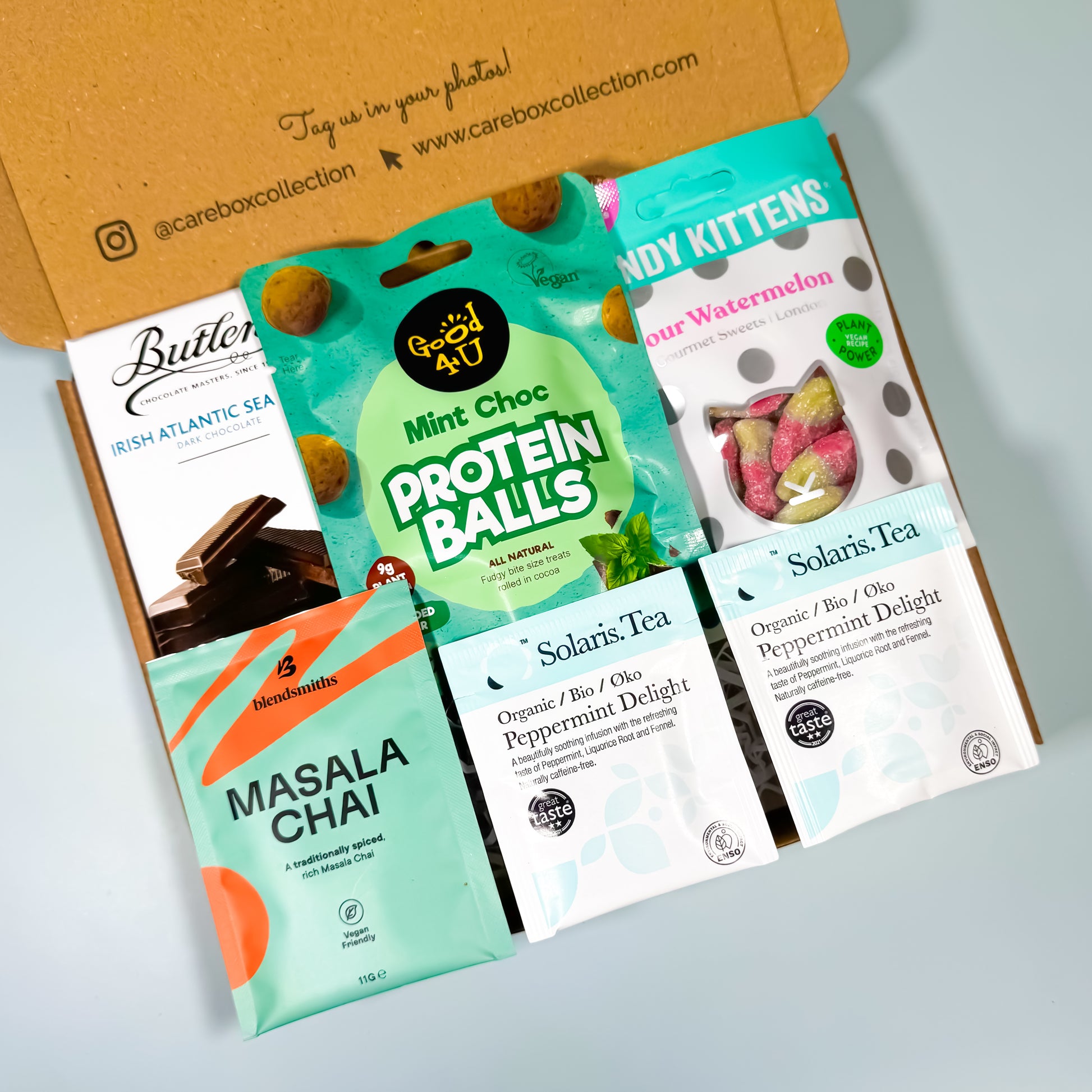 Open kraft gift box with mint-inspired treats and teas, including peppermint tea, chocolate, sweets, and protein balls. for birthdays or corporate gifts