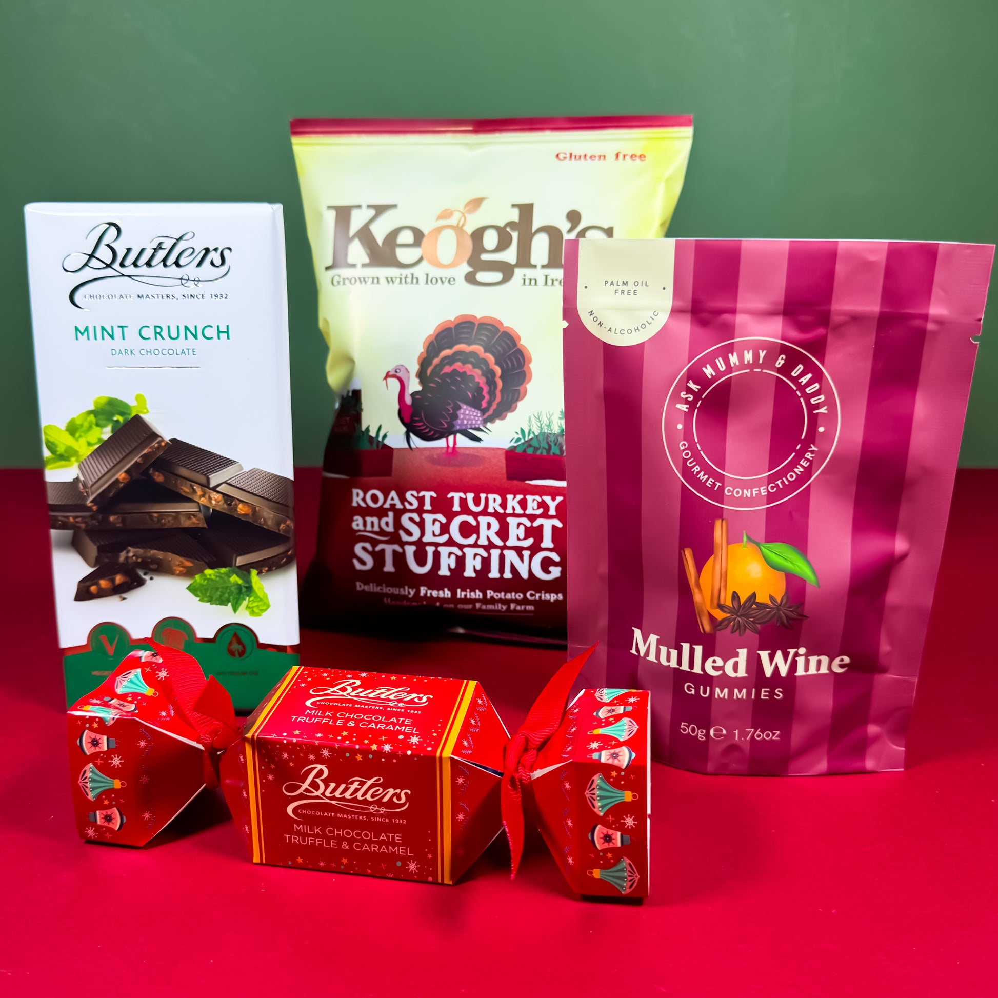 Christmas treat gift box with Butlers chocolate, Keogh’s roast turkey crisps, mulled wine gummies, and a Butlers chocolate cracker displayed on a festive red and green background