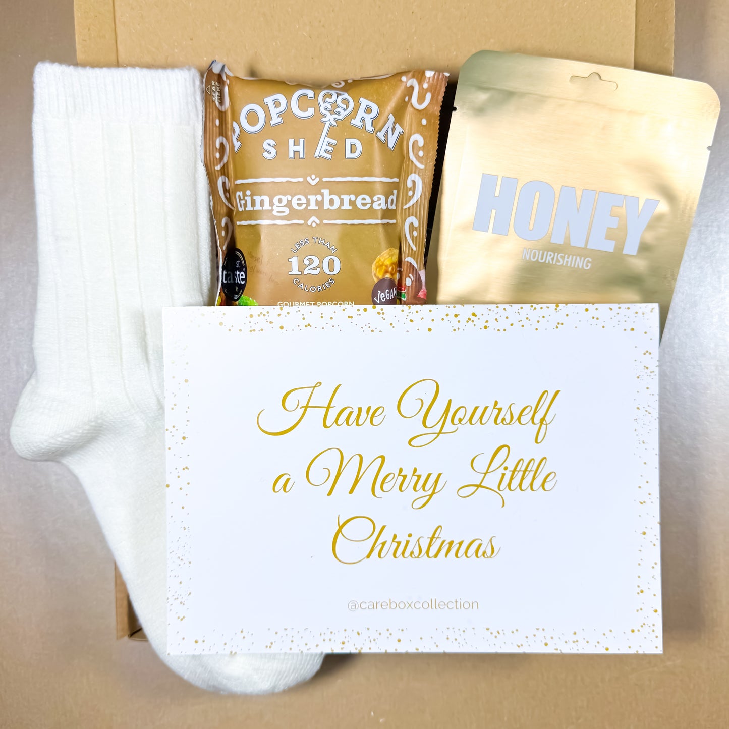 Warm Wishes Christmas Care Box with cosy socks, gingerbread popcorn, honey face mask and a festive “Have Yourself a Merry Little Christmas” card.