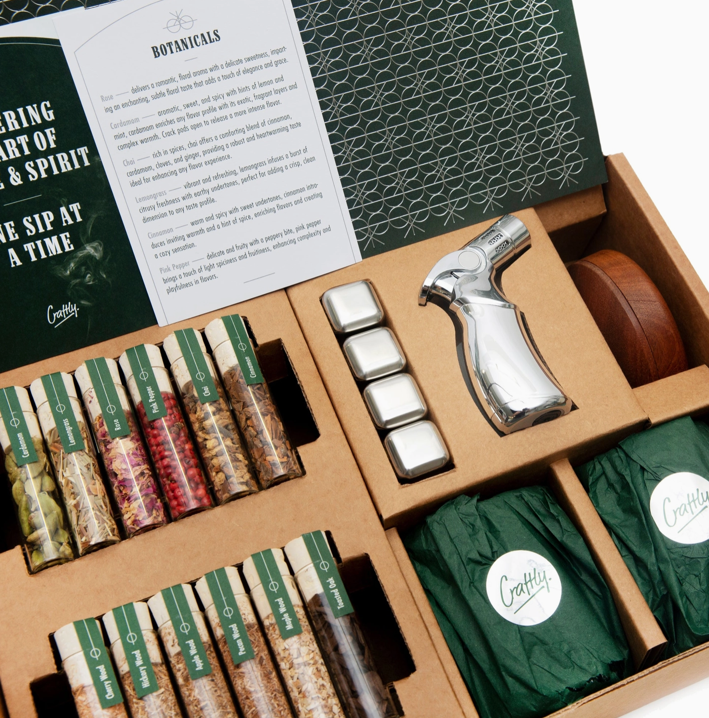 A premium whiskey smoker kit gift set with botanicals, wood chips, metal whiskey stones, a torch and smoker lid, presented in an organised gift box.